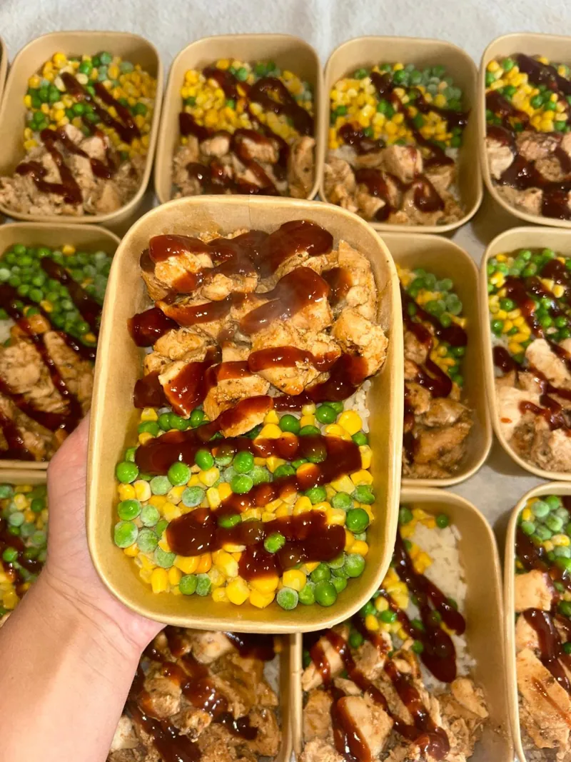 Jerk chicken with rice, peas and sweetcorn and BBQ sauce in a meal prep tub